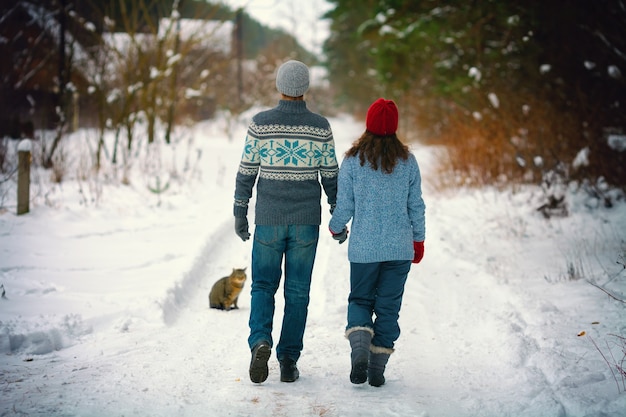 Jong koppel verliefd hand in hand wandelen op de besneeuwde weg in het dorp