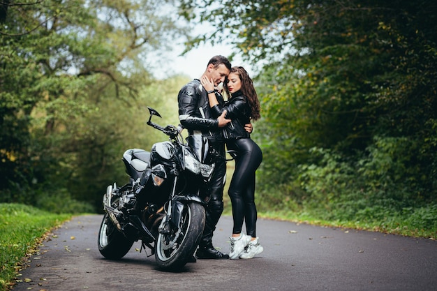 jong koppel verliefd op een motorfiets op de weg in het bos