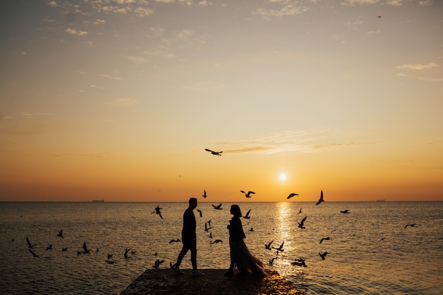 Jong koppel verliefd wandelen op het strand zonsopgang en meeuwen vliegen.