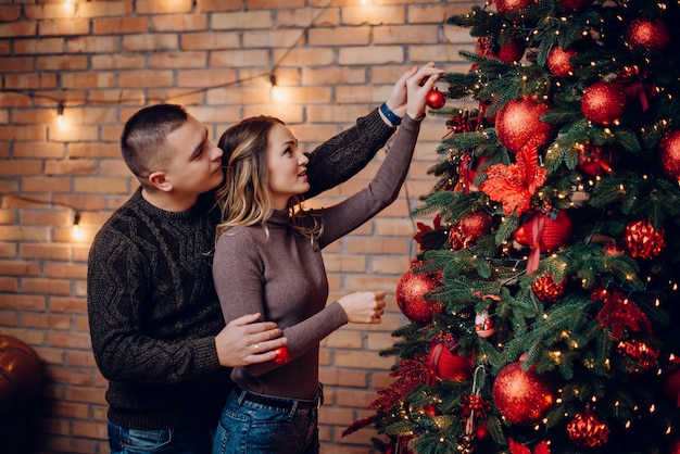 Jong koppel versieren kerstboom samen thuis