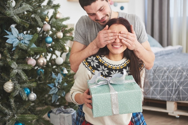 Jong koppel vieren Kerstmis. Een man presenteerde plotseling een cadeau aan zijn vrouw. Het concept van gezinsgeluk en welzijn