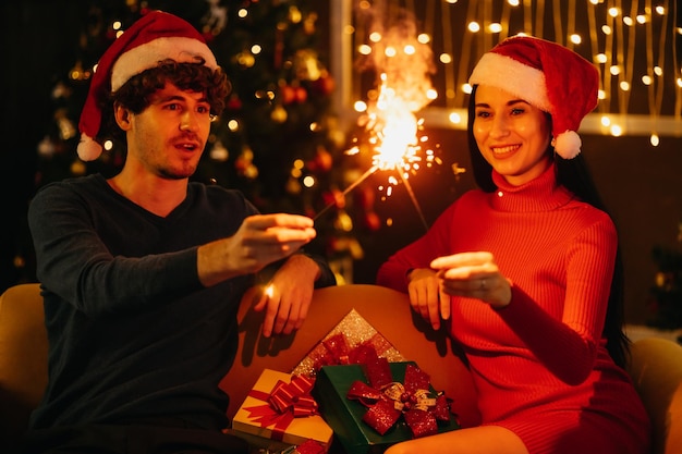 Jong koppel vieren oudejaarsavond met vonk en glanzend vuurwerk thuis.