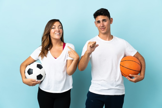 Jong koppel voetballen en basketballen op blauw trots en zelfvoldaan verliefd op jezelf concept