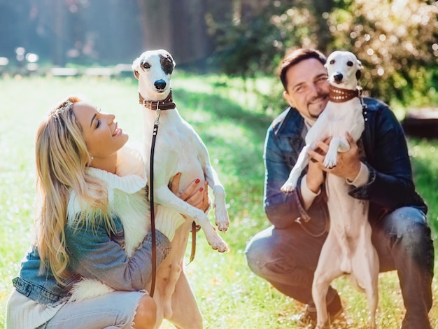 jong koppel vrouw en man in denim kleding wandelen met twee whippet honden buiten in de herfst