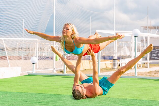 Jong koppel vrouw en mannen op veld fitness yoga oefening samen doen. Acroyoga-element voor kracht en balans