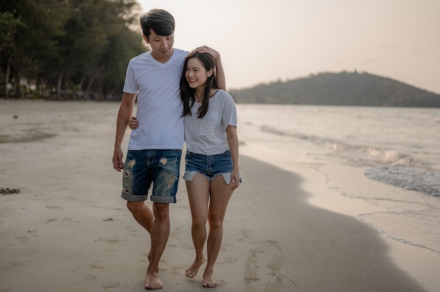 Jong koppel wandelen hand in hand met hun vriendin op het strand paar op zomervakantie