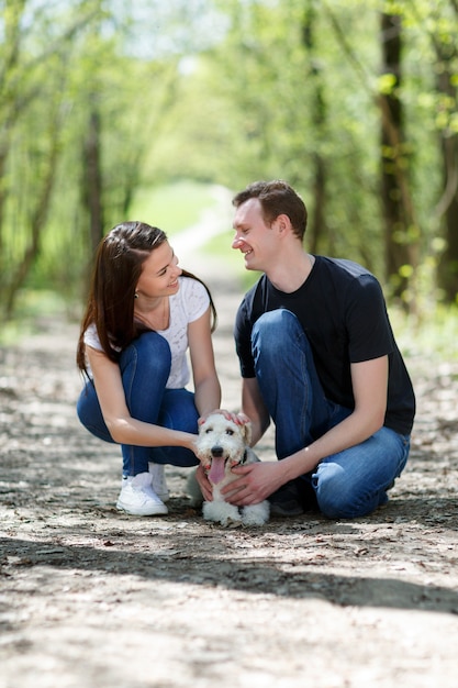 Jong koppel wandelen in het park met een fox terrier-hond