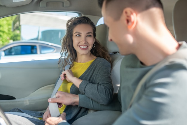 Jong koppel zitten in de auto en veiligheidsgordel bevestigen