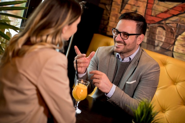 Jong koppel zitten in het café en het drinken van jus d'orange