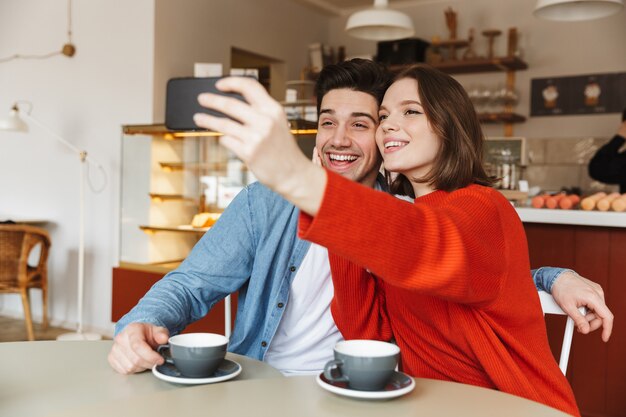 Jong koppel zittend aan een café tafel samen glimlachen