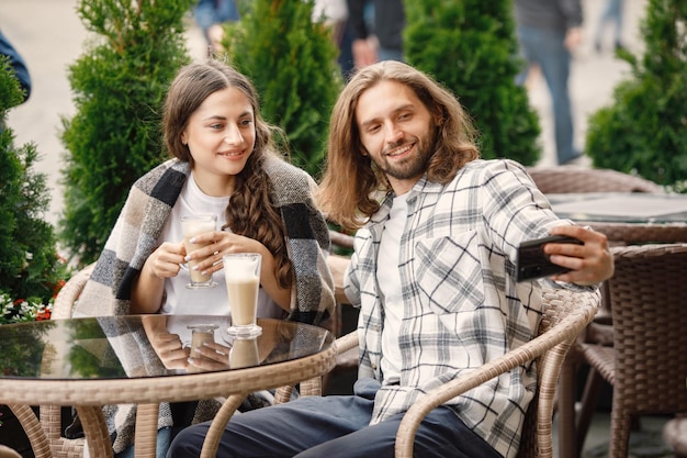 Jong koppel zittend in een café buiten genieten van koffie en een selfie maken