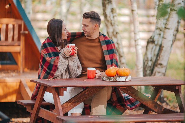 Jong koppel zittend op de houten oude tafel in de herfst bos van hun huis