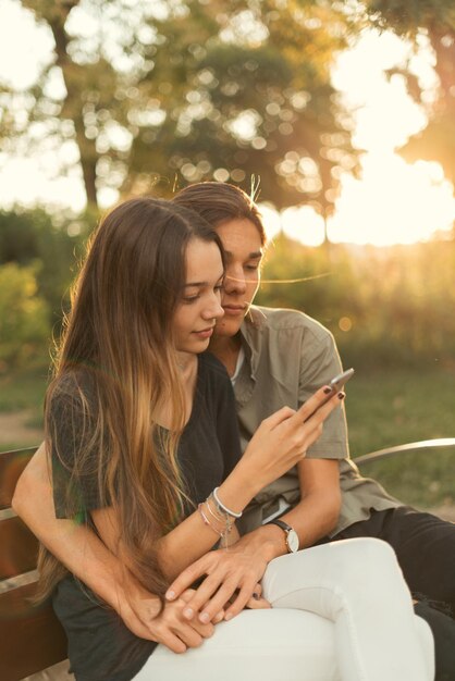 Jong koppel zittend op een bankje met behulp van mobiele telefoon