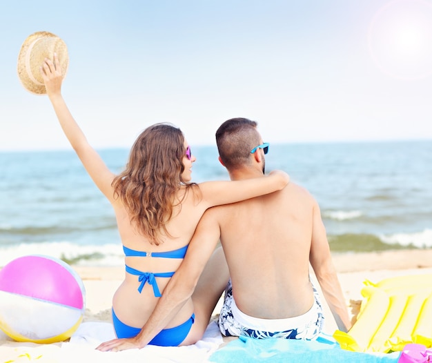 jong koppel zittend op het strand op een zonnige dag