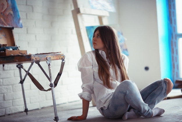 Jong kunstenaarsmeisje aan het werk in de workshop penseel schildert canvasinspiratie