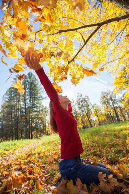 Jong lachend meisje gooit herfst esdoorn bladeren