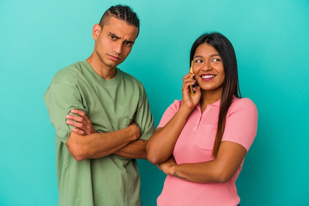 Jong Latijns paar met een mobiele telefoon die op blauwe achtergrond wordt geïsoleerd