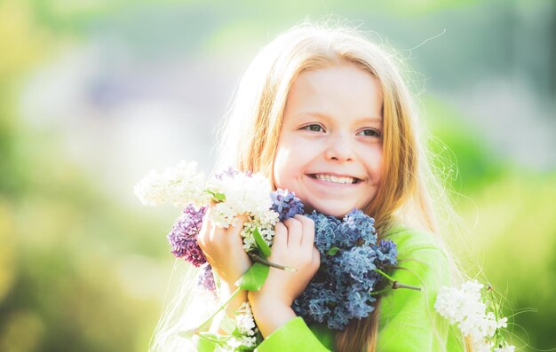 Jong lentemeisje in de lentetuin Jonge dame voelt zich gelukkig in de natuur Gezichtsportret van grappig tienermeisje Meisje met boeket van lila