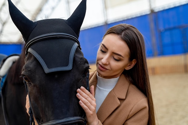 Jong levensstijlmodel in eenvormige jockey Mooie dame met paardportret