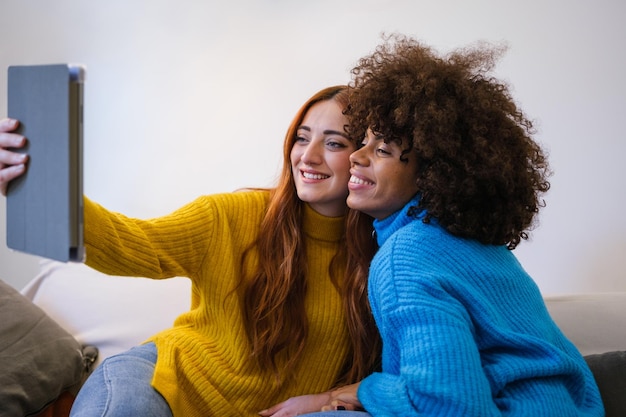 Jong lgtbi-stel dat samen een selfie maakt in hun nieuwe huis terwijl ze de tablet gebruiken en samen plezier hebben