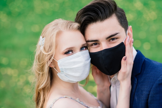 Jong liefdevol paar wandelen in medische maskers in het park tijdens quarantaine op hun trouwdag. Coronavirus, ziekte, bescherming, ziek, ziekte griep Europa-viering geannuleerd.