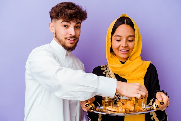 Jong Marokkaans koppel het drinken van thee vieren ramadan maand geïsoleerd op paarse achtergrond