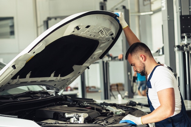 Foto jong mechanisch mannetje dat auto controleert