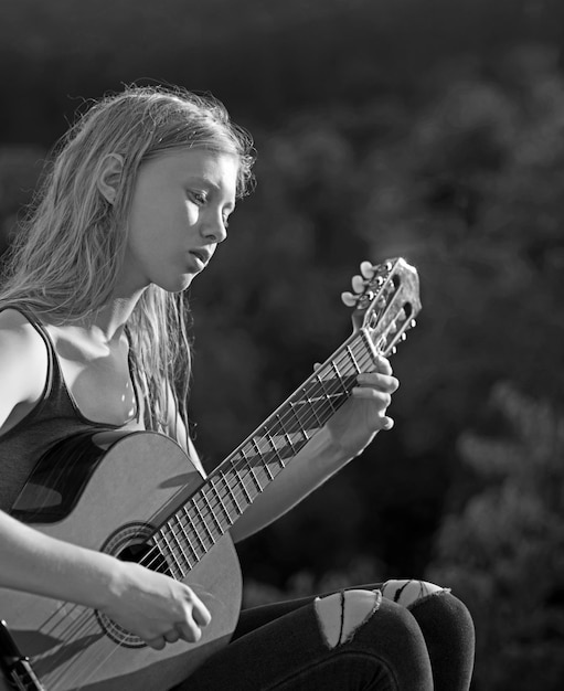 Jong meisje akoestische gitaar spelen in de bergen bij de zonsondergang