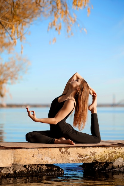 Jong meisje beoefenen van yoga oefening op rustige pier in herfst park