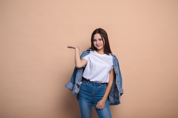 Jong meisje dat denimkleren draagt die op beige muur stellen