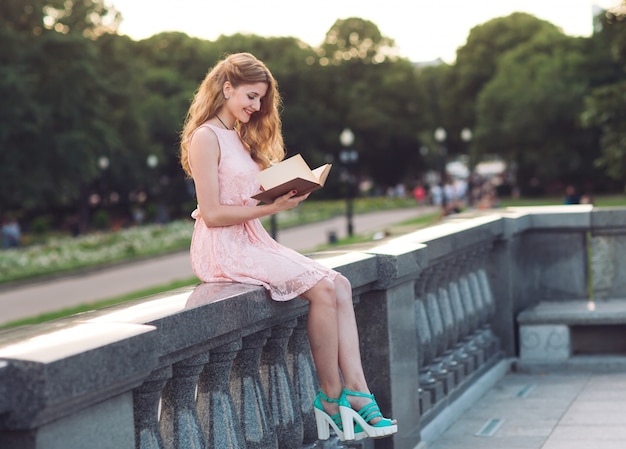 Jong meisje dat een boek in het park leest.