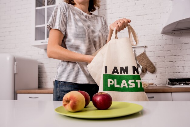 Jong meisje dat een doekzak houdt. Bij de keuken. Ik ben geen plastic.