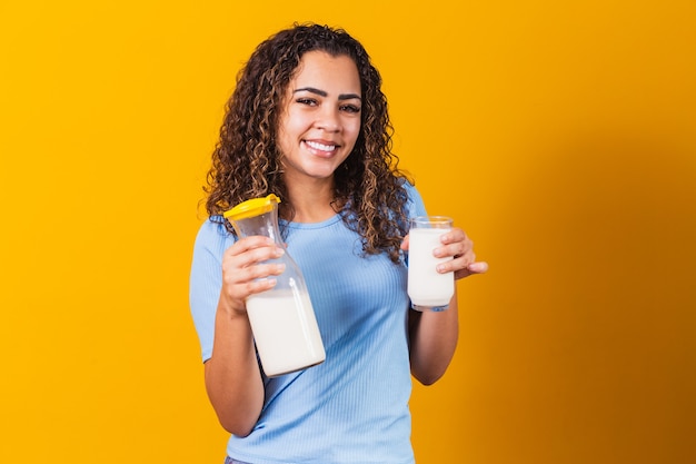 Jong meisje dat een glas melk drinkt en de volle fles vasthoudt.