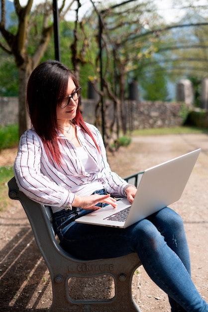 Jong meisje dat een shirt draagt en naar een laptop in een park kijkt