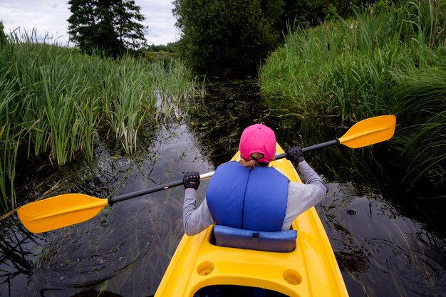 Jong meisje dat in roze GLB in kajak over de rivier roeit, erachter mening van