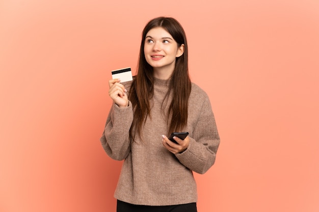 Jong meisje dat met mobiel met een creditcard koopt terwijl het nadenken