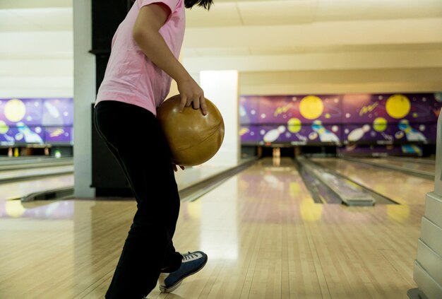 Jong meisje dat plezier heeft met een bal in de bowlingclub.