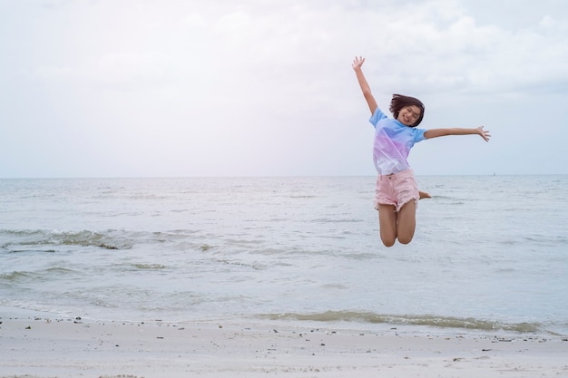 Jong meisje dat roze jeans draagt en bij het strand springt