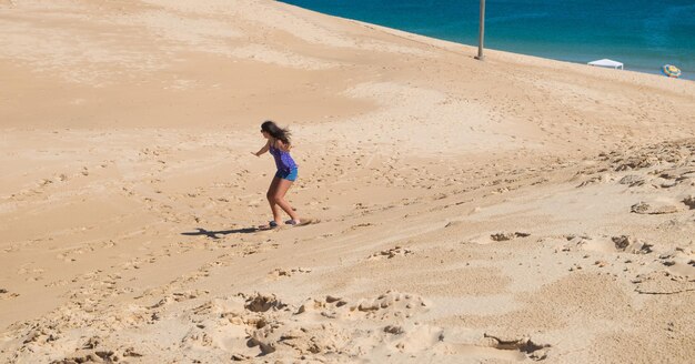 Jong meisje dat sandbord oefent in de duinen van Florianopolis, Brazilië