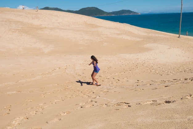 Foto jong meisje dat sandbord oefent in de duinen van florianopolis, brazilië