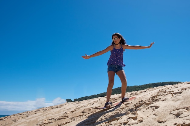 Jong meisje dat sandbord oefent in de duinen van Florianopolis, Brazilië