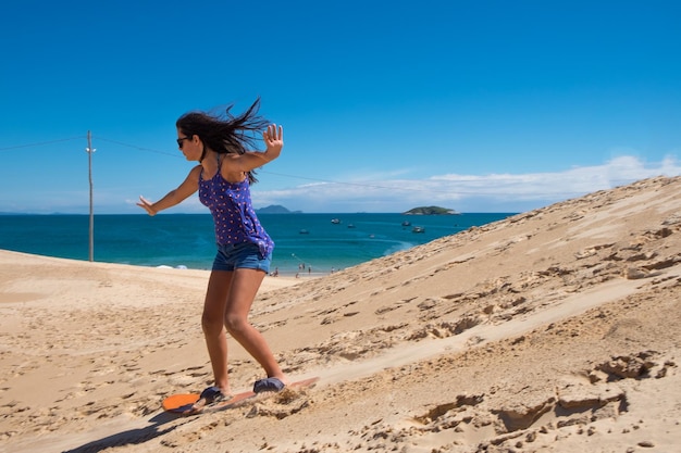 Jong meisje dat sandbord oefent in de duinen van Florianopolis, Brazilië