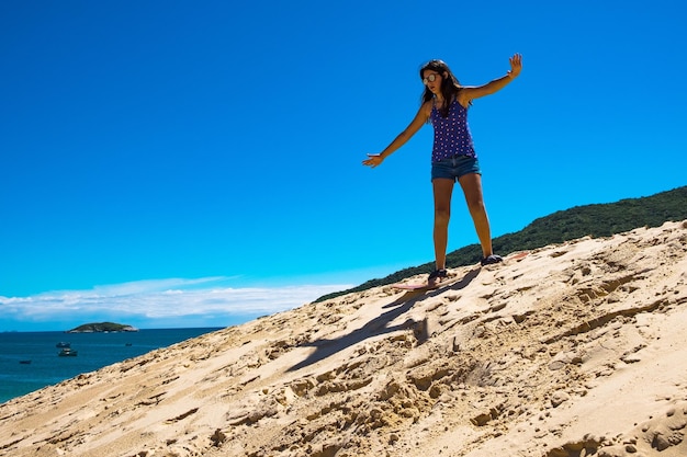 Jong meisje dat sandbord oefent in de duinen van Florianopolis, Brazilië