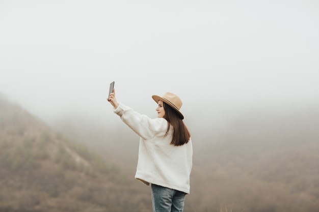 Jong meisje dat selfie buiten in de bergen op mistige dag.