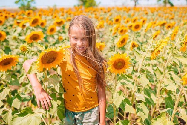 Jong meisje dat van aard op het gebied van zonnebloemen geniet.