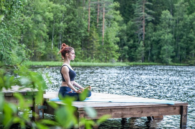 Jong meisje dat yoga beoefent in de natuur aan het meer Vrouwelijk geluk Landschapsachtergrond