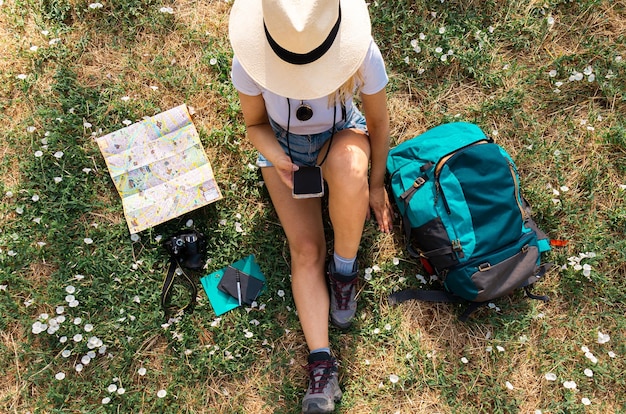 Jong meisje dat zit plant haar volgende reis en typt op smartphone digitale nomade