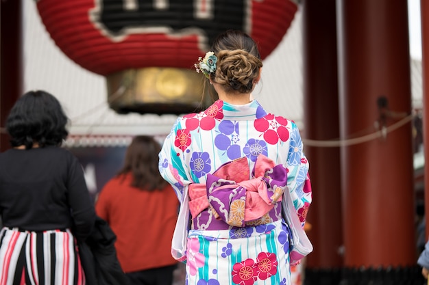 Jong meisje die Japanse kimono dragen die zich voor Sensoji-Tempel in Tokyo bevinden