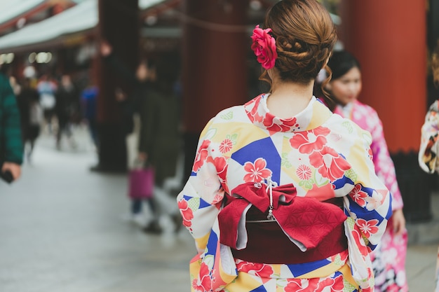 Jong meisje die Japanse kimono dragen die zich voor Sensoji-Tempel in Tokyo bevinden,