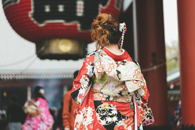 Jong meisje die japanse kimono dragen die zich voor sensoji-tempel in tokyo bevinden,